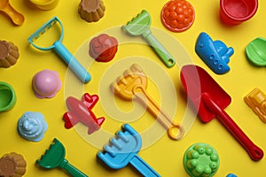 Beach sand toys on yellow background, flat lay