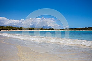 Beach scene with clear blue water, blue sky and sandy shore seen from Puerto Rico