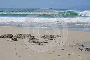 Beach scene with rocks in the foreground and waves breaking in the background