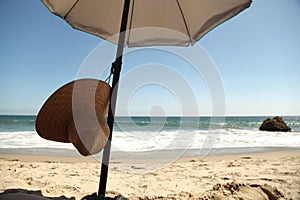 Beach scene. Straw Hat and Umbrella on Sand.