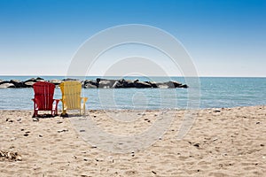Beach scene with two colorful adirondack chairs