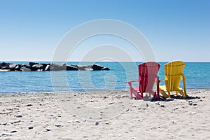 Beach scene with two colorful adirondack chairs photo