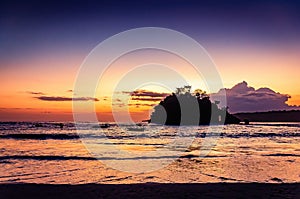 Beach and sea after sunset with a small island in the water. Tropical island and local fisherman boats in the ocean during sunset