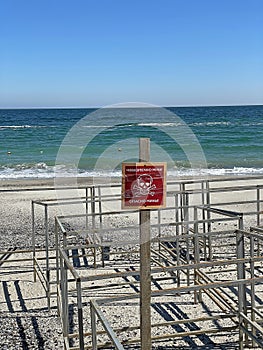 The beach and the sea with a warning sign in Ukrainian and Russian \