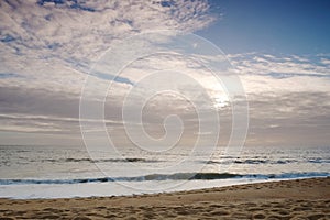 Beach shore. View of sand and sky with sun and clouds