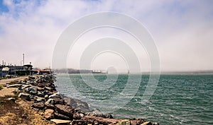 Beach side with rocks and jetty on san Francisco Bay with Golden gate bridge in the background