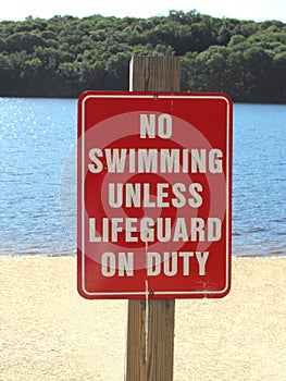 Beach sign warning no swimming unless lifeguard on duty