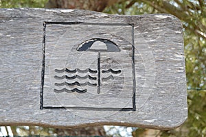Beach sign on wood. Parasol and waves drawn on wood. photo
