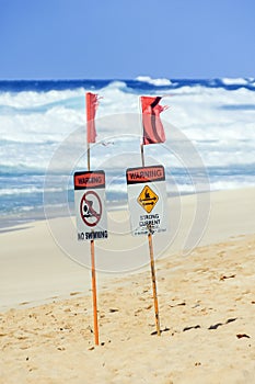Beach signs prohibiting swimming and warning of strong currents at the beach on the north shore of Oahu, Hawaii