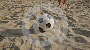 Beach soccer. A man hits a classic black-and-white leather ball. Rest outside. Summer sports. An active lifestyle