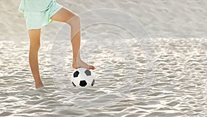 Beach soccer on sand. Bare feet of football player boy and ball on sandy sea shore. Sports games, summer holidays