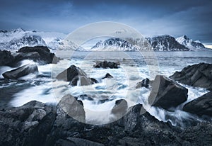 Beach with stones in blurred waves, blue sky with low clouds