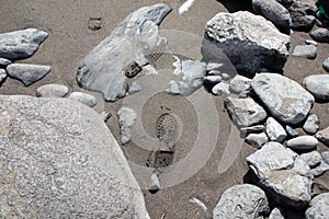 Beach with stones and sand and footprints