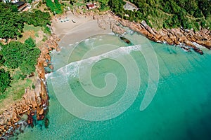 Beach, stones and transparent ocean in Brazil. Aerial view of tropical beach in Florianopolis