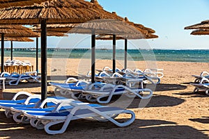 Beach with straw umbrellas and sunbeds. Egyptian resort in Sharm el Sheikh.