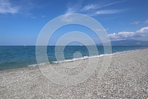 Beach on a summer day, blue sea and sky with white clouds, vacation at the sea, Calabria, Italy