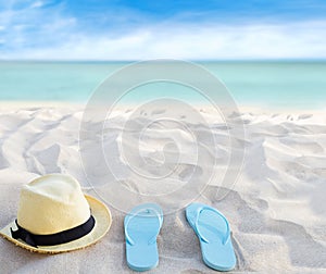 Beach summer holiday background. Flip flops and hat on sand near ocean. Summertime accessories on seaside. Tropical vacation