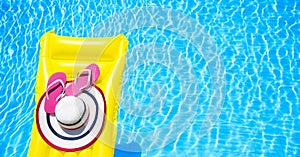 Beach summer holiday background. Inflatable air mattress, flip flops and hat on swimming pool. Yellow lilo and summertime