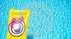 Beach summer holiday background. Inflatable air mattress, flip flops and hat on swimming pool. Yellow lilo and summertime