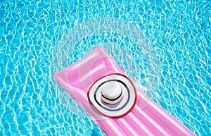 Beach summer holiday background. Inflatable air mattress and hat on swimming pool. Pink lilo and summertime accessories