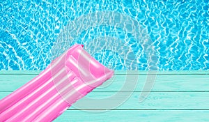 Beach summer holiday background. Inflatable air mattress on swimming pool water. Pink lilo and summertime accessories on poolside