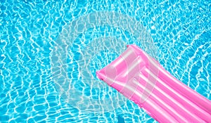 Beach summer holiday background. Inflatable air mattress on swimming pool water. Pink lilo and summertime accessories on poolside