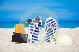 A Beach summer holiday banner background. Flip-flops and hat with a board and ball on the sand near the ocean. Summer accessories