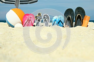 A Beach summer holiday banner background. Flip-flops and hat with a board and ball on the sand near the ocean. Summer accessories