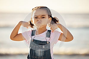 Beach, summer and little girl pulling funny face and flexing on holiday in Mexico. Strong, courage and child at ocean on