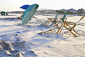 Beach summer scene at end of day in watercolor leaning green beach umbrella and empty green beach chairs