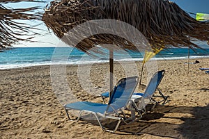 Beach sun beds and straw umbrella on Milos beach on Lefkada island, Greece -