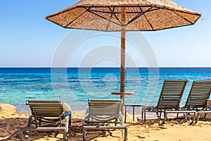 Beach with sunbeds and umbrellas against the background of the sea horizon. The bright blue sea. Snorkeling on the Red Sea in