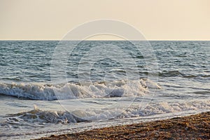 Beach on a Sunny summer day during sunset. Landscape with sea sunset on beach. The sea wave came ashore in a sunset color. In the
