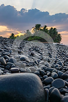 Beach at sunrise with dark rocks in the foreground - vertical.