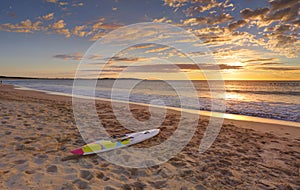 Beach sunrise and paddleboard on shoreline