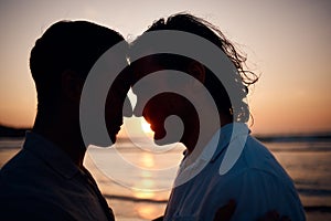 Beach, sunset and gay couple in silhouette, embrace and love on summer island vacation together in Thailand. Sun, ocean