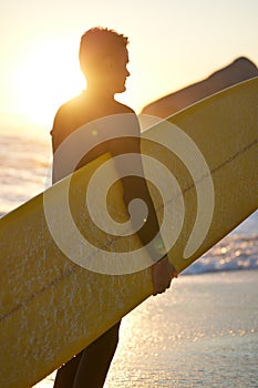 Beach, surfer and man with a surfboard at sunset thinking of of fitness training, workout or water sport exercise