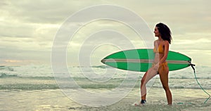 Beach, surfer in summer and woman walking with surfboard on sand by sea or ocean for travel. Smile, bikini and morning