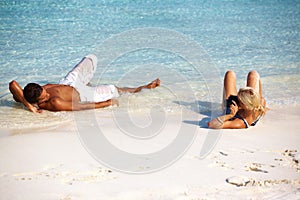Beach, tanning and couple relax on holiday in summer on vacation in Hawaii island by water. Travel, lying and sand