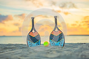 Beach tennis racket and ball on the sandy beach.. Background with copy space. Sport court at the beach and ball. Summer