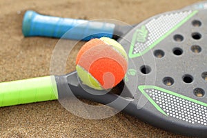Beach tennis rackets and ball on sand