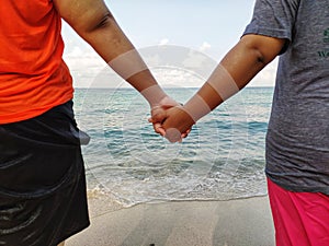 At the beach there are lovers holding hands to walk down to the sea. Summer concept.