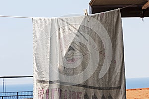 A beach towel hanging out in the sun on a terrace facing the sea. Vacation, attic.