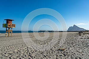 Beach with a tower of the coast guard with the Rock of Gibraltar in the background