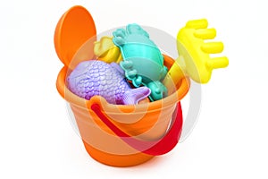 Beach toys: children`s sea bucket with orange scoop, yellow rake, and molds isolated on white background