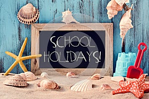 Beach toys, seashells, starfishes and text school holidays