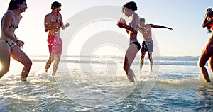 Beach, travel and friends playing in ocean together for fun with energy on vacation or holiday in summer. Splash, wave
