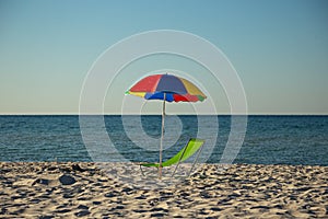 Beach umbrella and chair on the background of the sea