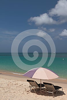 Beach umbrella and chaise lounges on seashore. St. George`s, Grenada