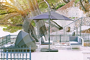 Beach umbrella and chaise for relax and comfort on balcony of hotel on sea coast.